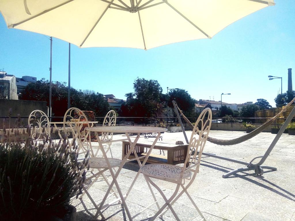 uma mesa e cadeiras com um guarda-sol e um baloiço em Casa do Sol no Porto