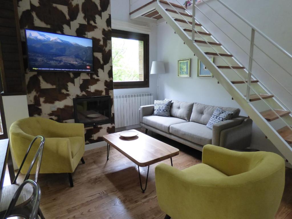 a living room with a couch and chairs and a staircase at Pleta del Mon Atico in Benasque