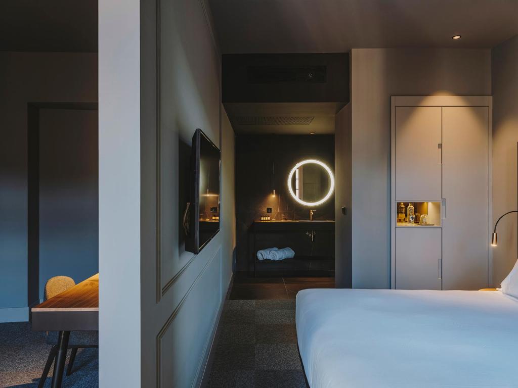 a bedroom with a white bed and a mirror at El Môderne Hotel in Gijón
