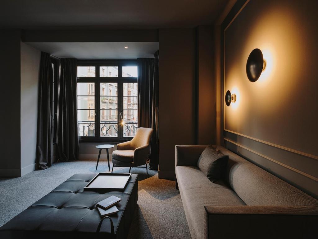a living room with a couch and a chair and a window at El Môderne Hotel in Gijón