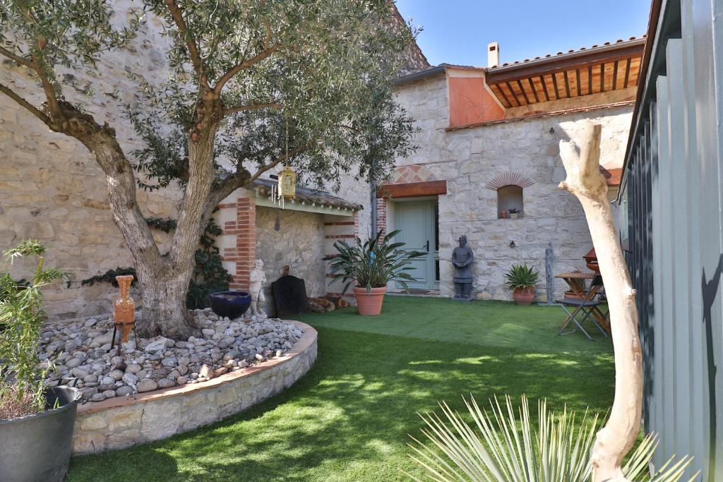 un jardín con un árbol y una casa de piedra en VILLA ARTEMIA Maison vigneronne - chambre d hôtes-B&B-piscine et spa, en Sigean