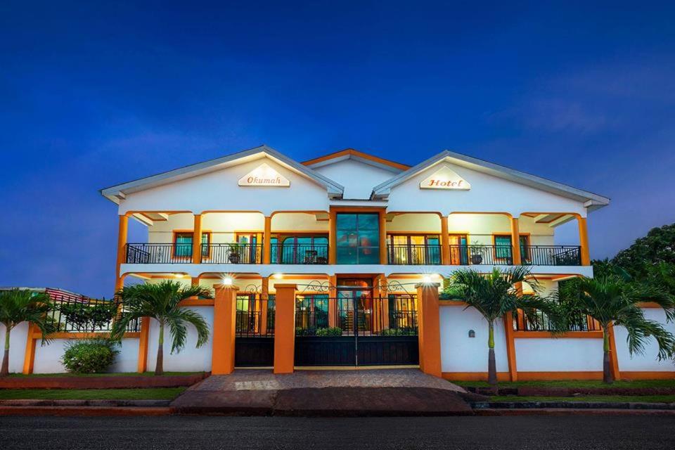 una grande casa bianca con palme di fronte di Okumah Hotel a Kumasi