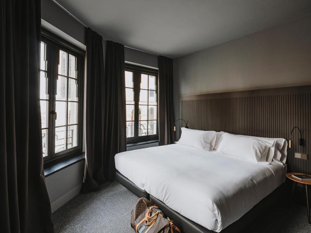 a bedroom with a large bed and two windows at El Môderne Hotel in Gijón