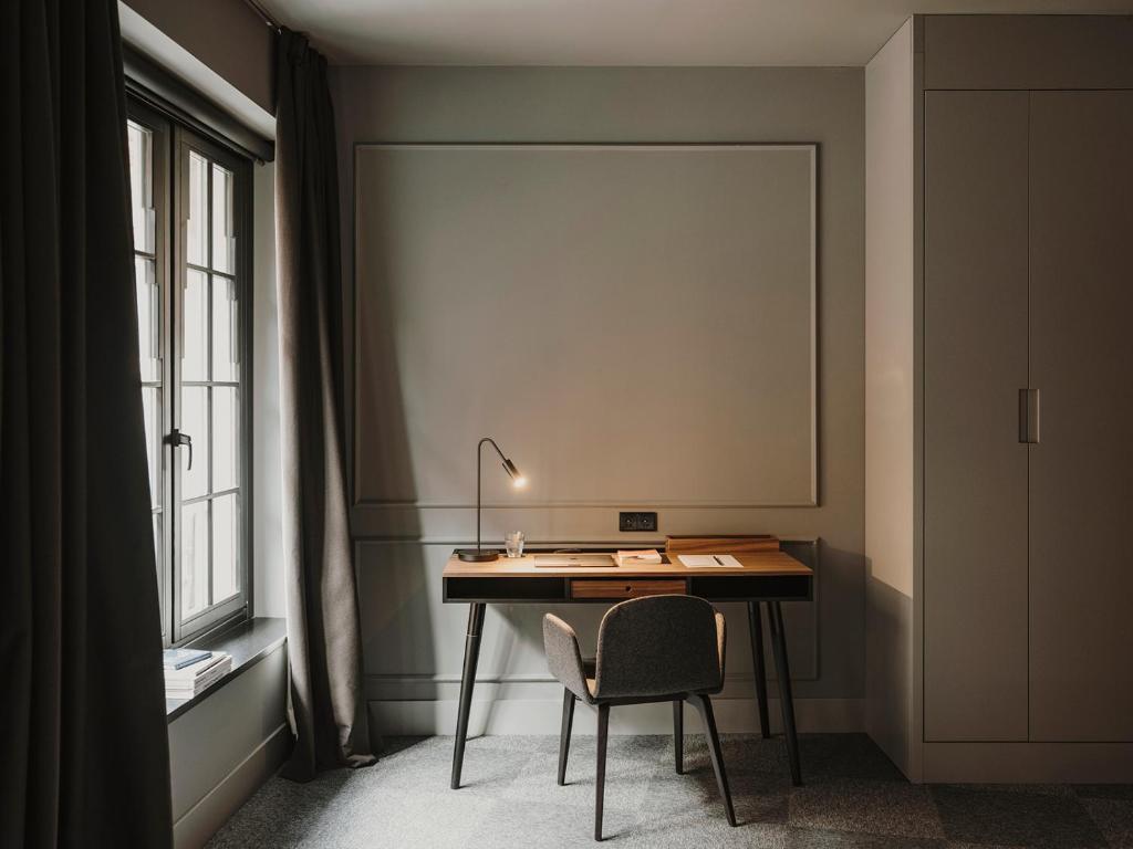 a desk with a lamp and a chair next to a window at El Môderne Hotel in Gijón