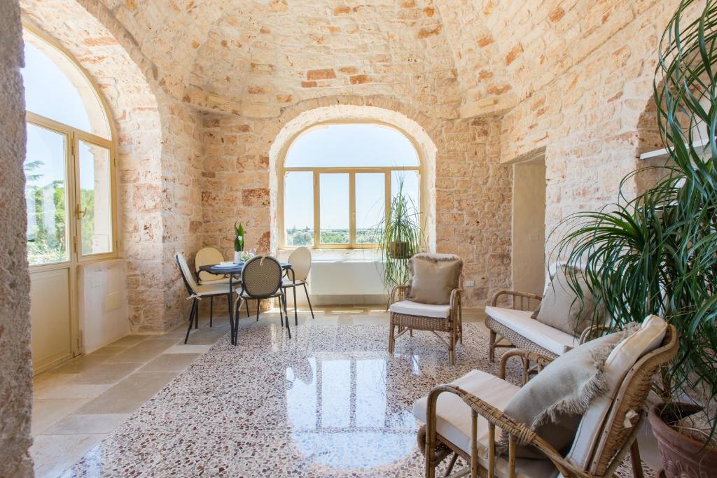 een woonkamer met een tafel en stoelen en een bakstenen muur bij Masseria Castelluzzo in Ceglie Messapica