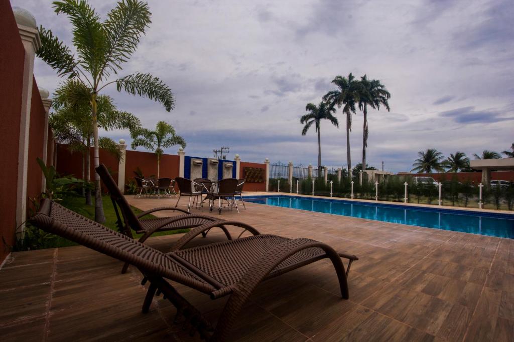 a patio with chairs and a swimming pool and palm trees at Hotel Encosta do Horto in Juazeiro do Norte