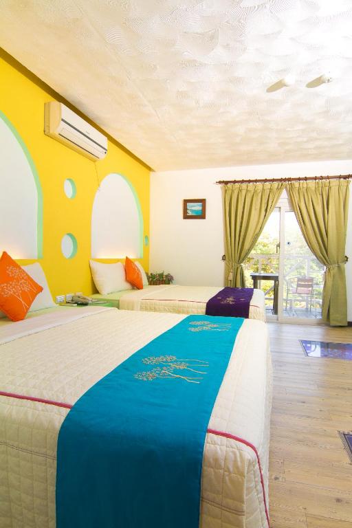 two beds in a room with yellow walls at Ocean Star B&amp;B in Kenting