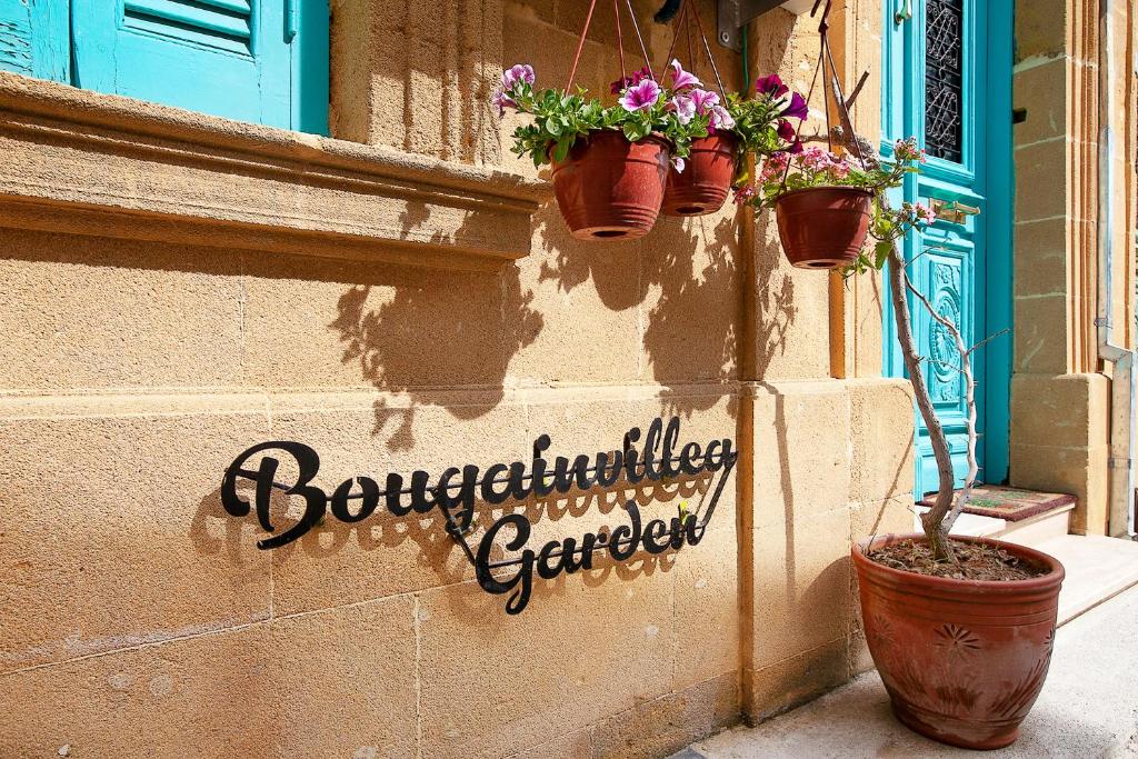 a sign on the side of a building with potted plants at Bougainvillea Garden in Lefkosa Turk