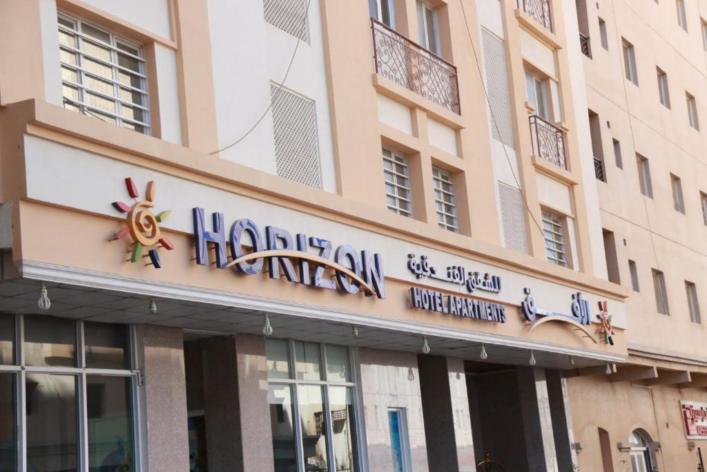 a building with a sign for a restaurant at Horizon Hotel Apartments - الأفق للشقق الفندقية in Al Khawḑ