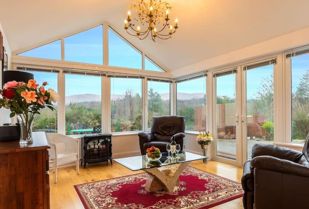 a living room with a table and chairs and windows at Salmons Leap Sneem Village Kerry in Sneem