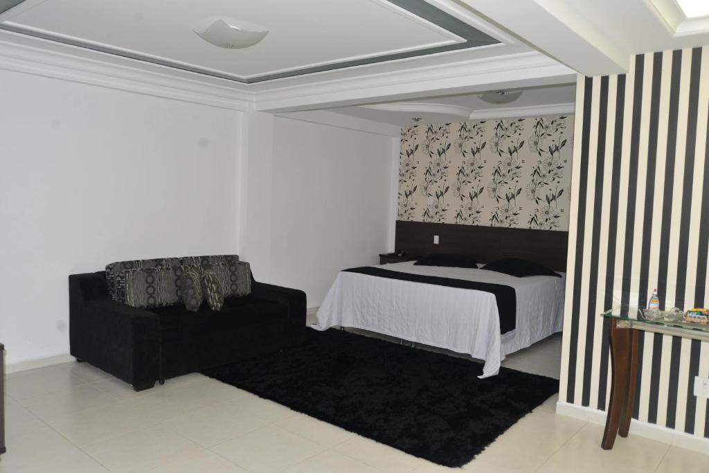 a bedroom with a bed and a black couch at Del´Fiori Hotel in Ubá