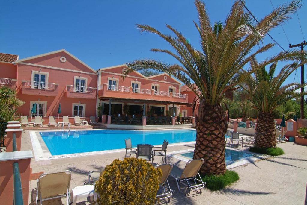 a resort with a pool and palm trees and chairs at Joy Hotel in Sidari