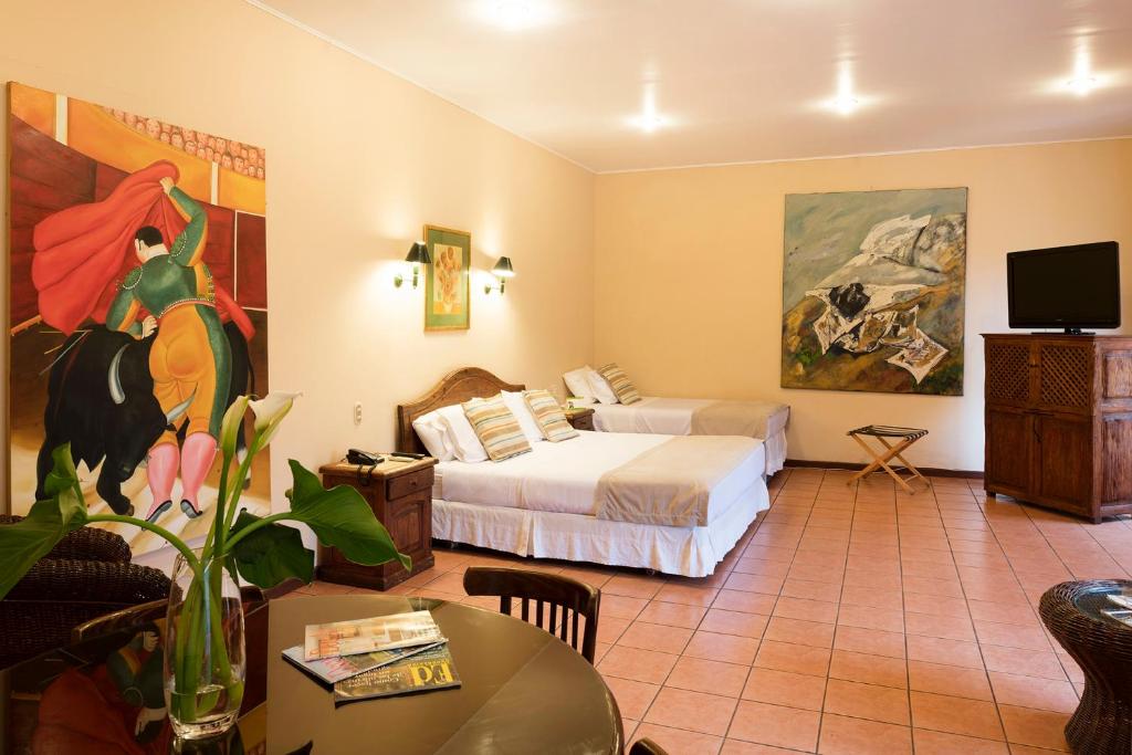 Una habitación de hotel con dos camas y un televisor. en Hotel Americano, en Arica