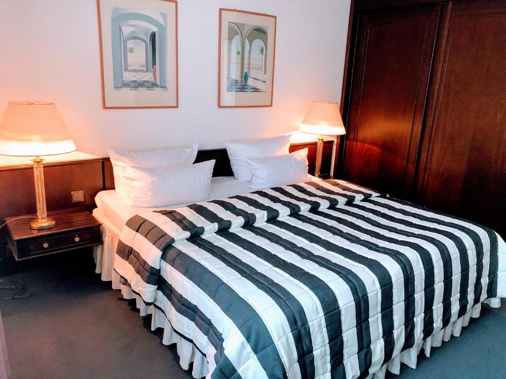 a hotel room with a bed with a striped blanket at Hotel Kölner Hof in Dormagen