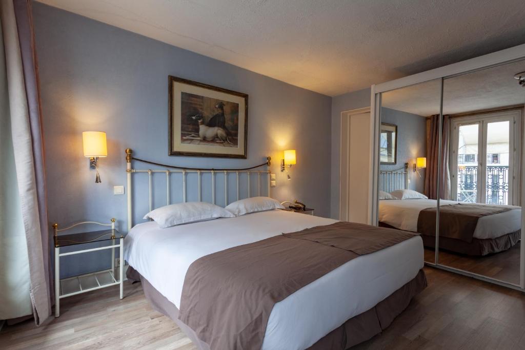 a bedroom with two beds and a mirror at Hôtel Atlantis in Paris