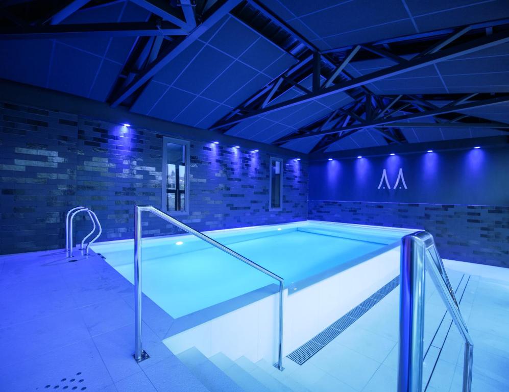 a swimming pool in a room with blue lights at Le Magic Hôtel & Spa in Vitré
