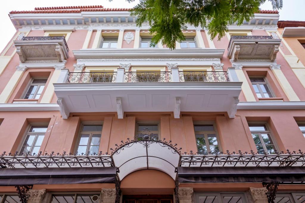 un edificio rosa con balconi e balcone di Emporikon Athens Hotel ad Atene