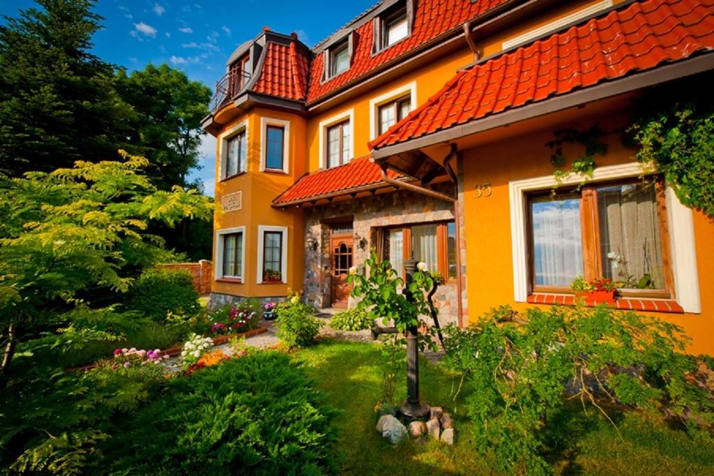 une maison orange avec un jardin en face de celle-ci dans l'établissement Villa Akacja, à Łeba