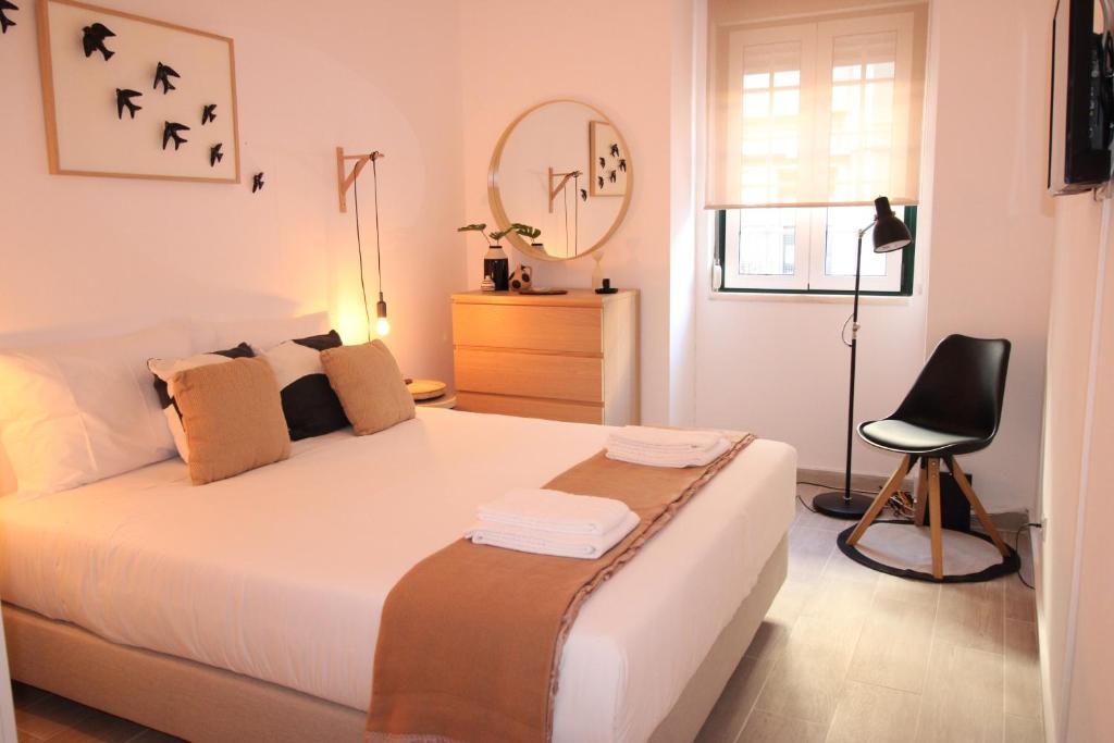 - une chambre avec un lit, une chaise et un miroir dans l'établissement Apartamento nas Olaias a 5 minutos da Faculdade ISEL e IST, à Lisbonne