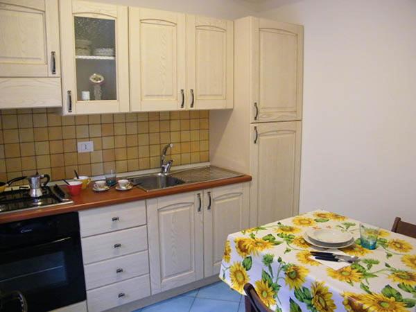 uma cozinha com armários brancos, uma mesa e um lavatório em Appartamento Garibaldi 142 em Castellammare del Golfo