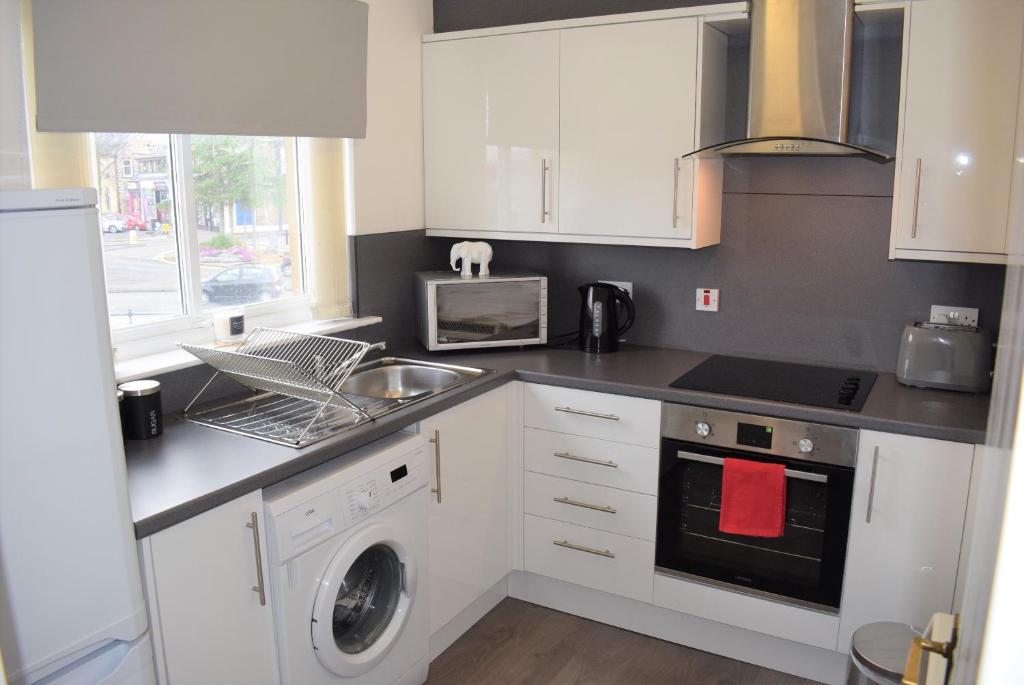 uma cozinha com um lavatório e uma máquina de lavar roupa em Kelpies Serviced Apartments Alexander- 2 Bedrooms em Falkirk