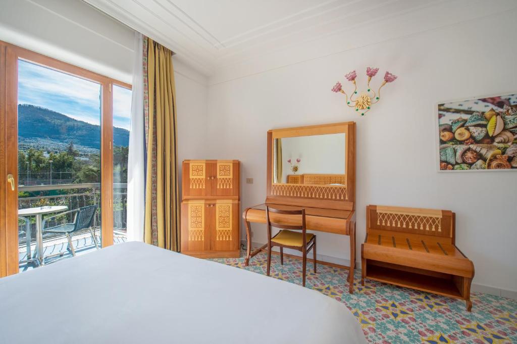 a bedroom with a bed and a desk and a mirror at Grand Hotel Flora in Sorrento