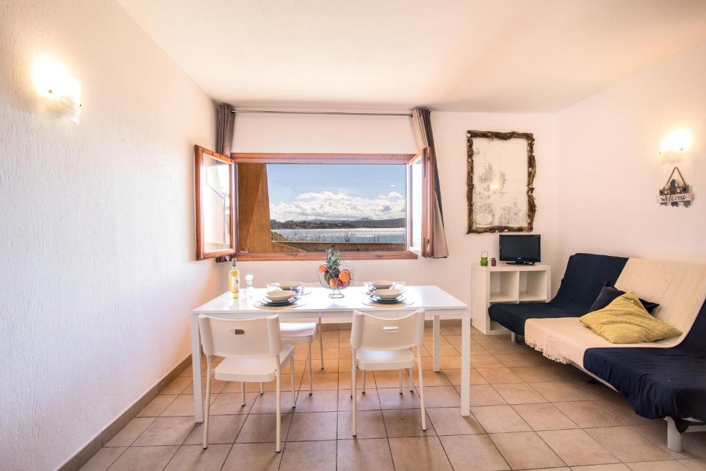 un soggiorno con tavolo, sedie e divano di Homey Experience - Sea Corner Apartment a La Maddalena