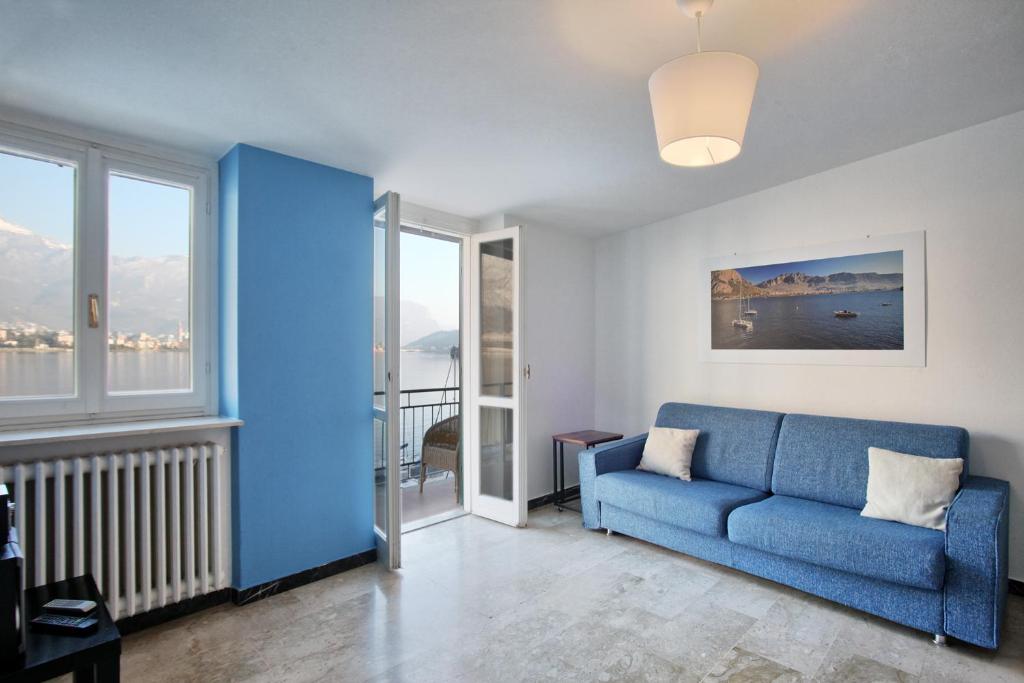 a living room with a blue couch and windows at COZY LAKE COMO APARTMENTS in Valmadrera