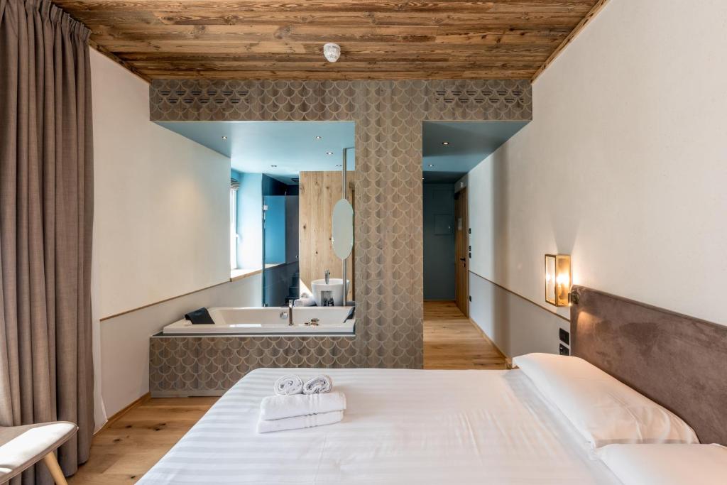 a bedroom with a large bed and a tub at Good Life Hotel Garden in Ledro