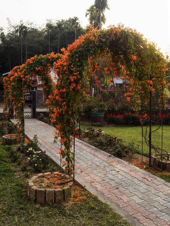 a garden with an arch with orange flowers on it at Bononi in Jorhāt