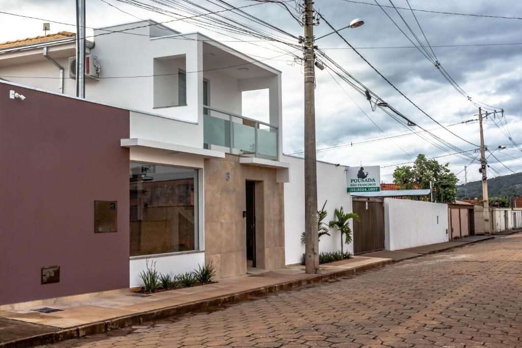 uma casa branca numa rua de calçada em Pousada São Francisco em São João Batista do Glória