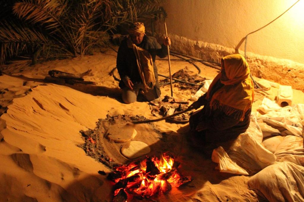 two people standing around a fire in the sand at Maison Proche De Désert Douz in Douz