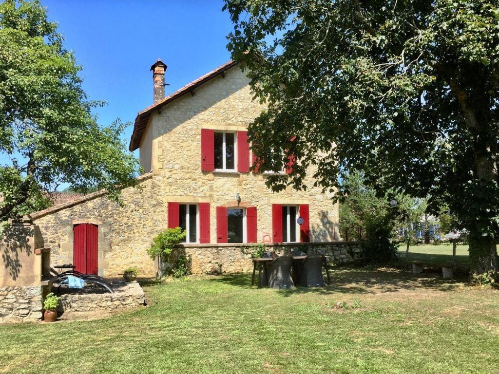 an old stone house with red shutters and a yard at RUDELLE in Thénac