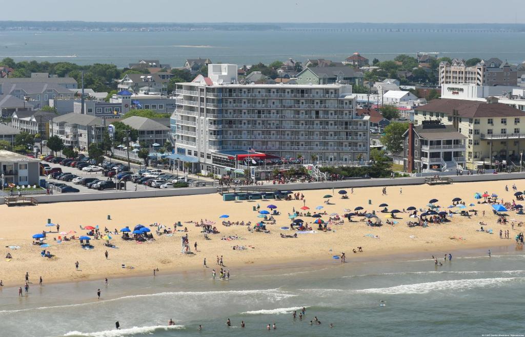 un groupe de personnes sur une plage avec parasols dans l'établissement Commander Hotel & Suites, à Ocean City