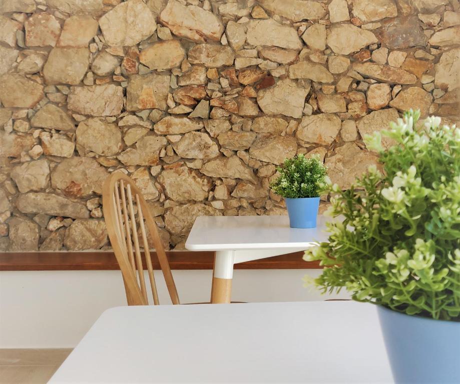 a table and a chair and a stone wall at Pure Fonte Velha B&B in Vila do Bispo