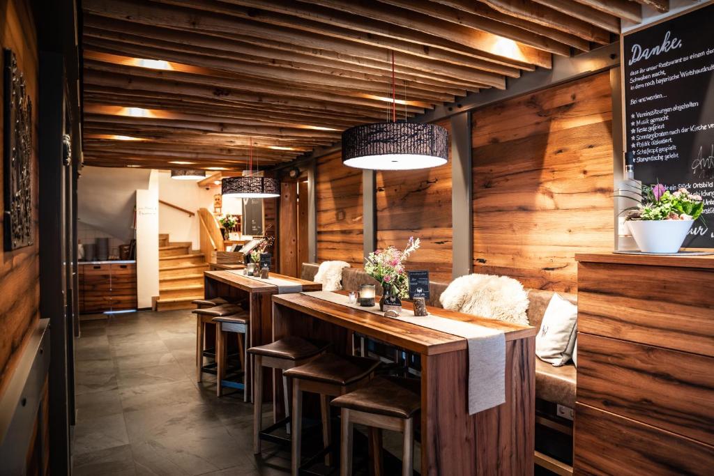 a restaurant with wooden walls and a bar with stools at Gasthof Adler in Ziemetshausen