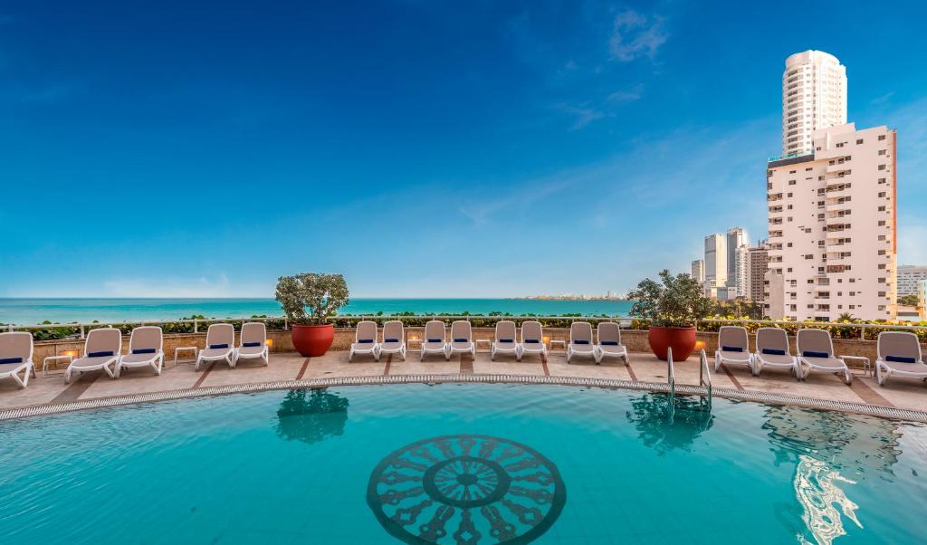 a swimming pool with lounge chairs and the ocean at Hotel Almirante Cartagena Colombia in Cartagena de Indias