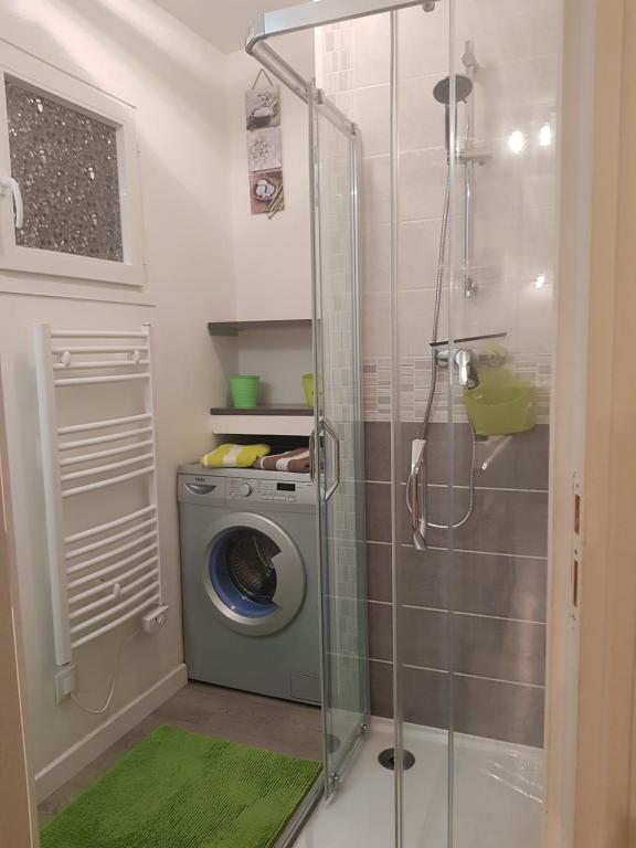 a shower with a washing machine in a bathroom at Cottage sword beach in Hermanville-sur-Mer