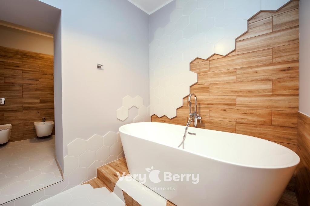 baño con bañera blanca y paredes de madera en Very Berry - Podgorna 1c - Old City Apartments, check in 24h, en Poznan