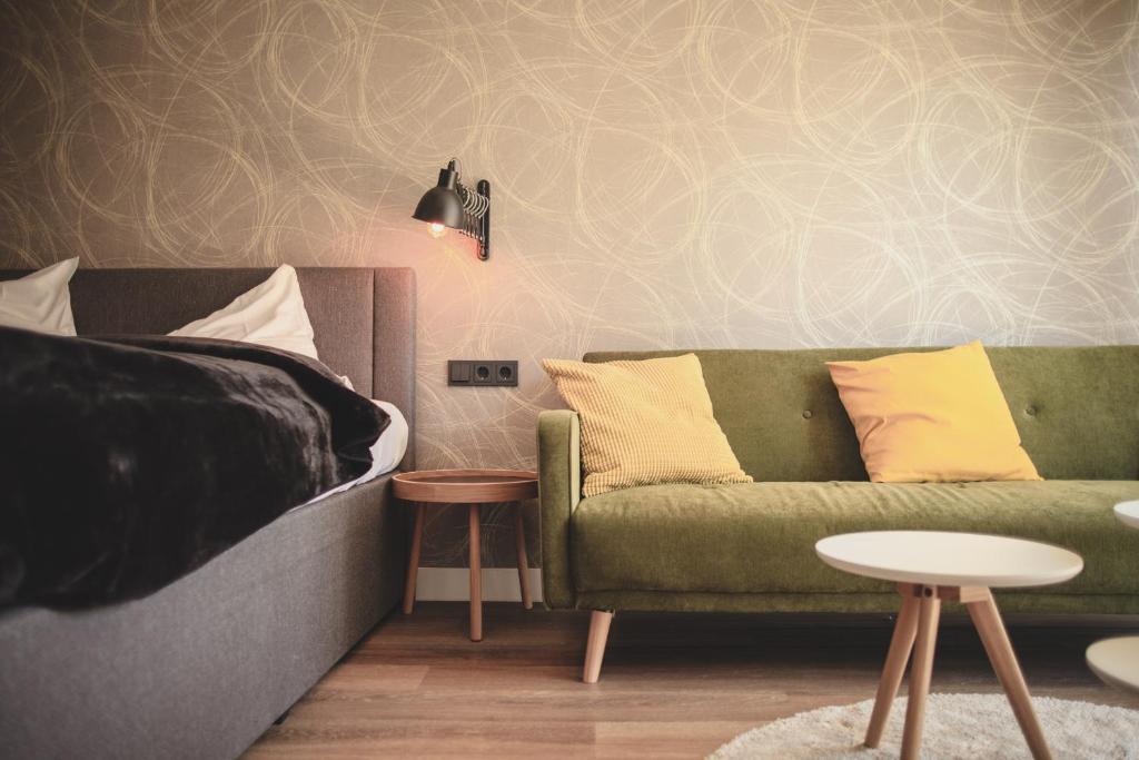 sala de estar con sofá verde y cama en Niteroom Boutiquehotel & Apartements, en Duisburg