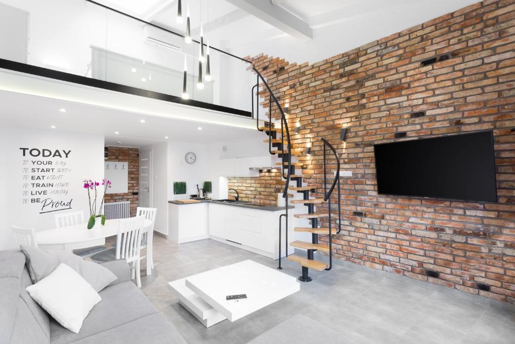 a living room with a brick wall and a tv at WUCHTA WIARY Apartment in Poznań