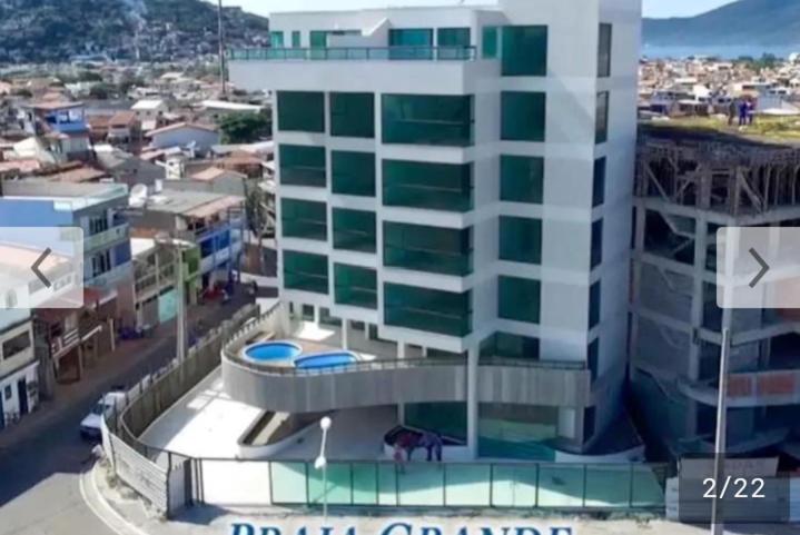 a tall building with a pool in front of it at Apartamento Sophia 1 in Arraial do Cabo