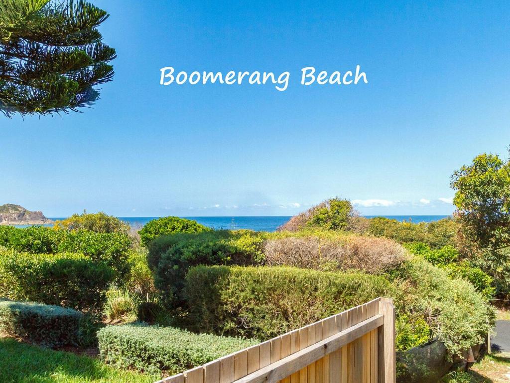 een uitzicht op de oceaan vanaf een strand met een houten hek bij Oceanside 18 in Blueys Beach