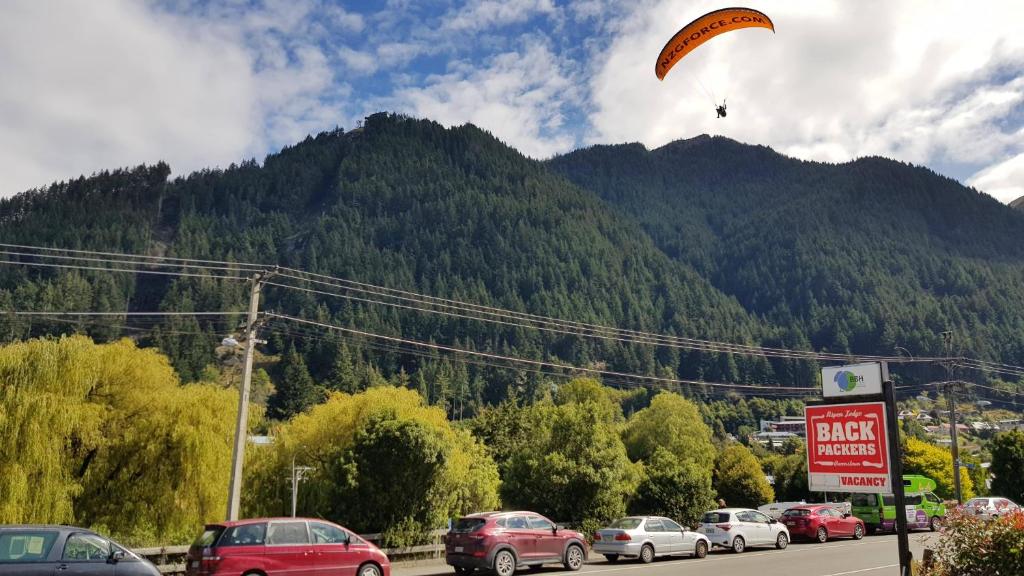 a paraglider is flying over a parking lot at Aspen Lodge Backpackers in Queenstown