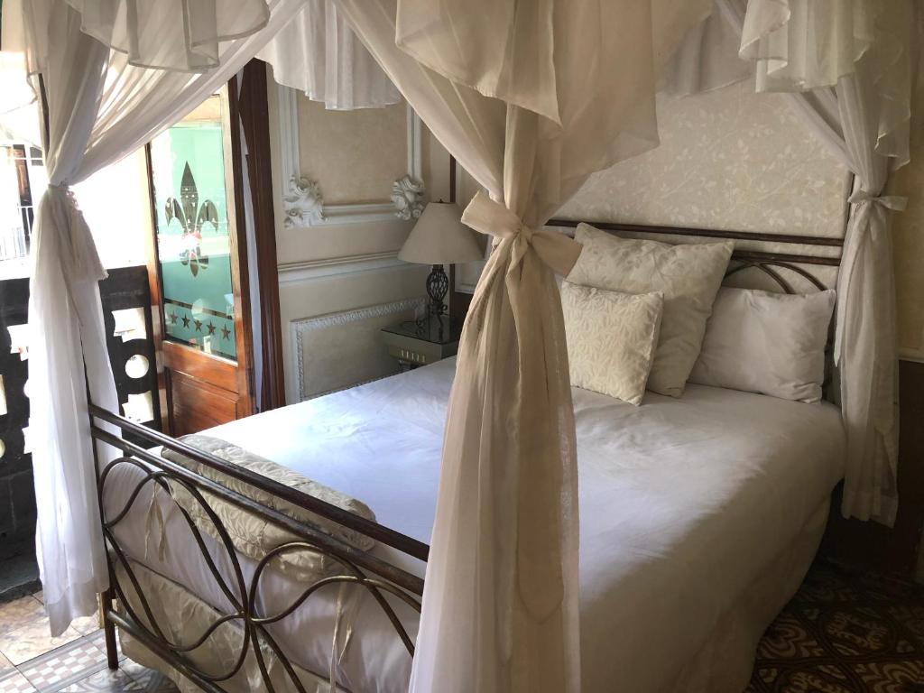 1 dormitorio con 1 cama blanca con dosel en Hotel Elena, en Puebla