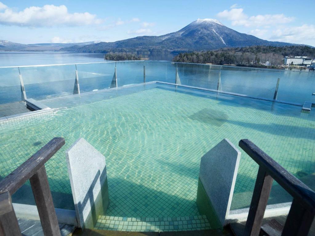 a swimming pool with a view of a mountain at Akan Yuku no Sato Tsuruga in Akankohan