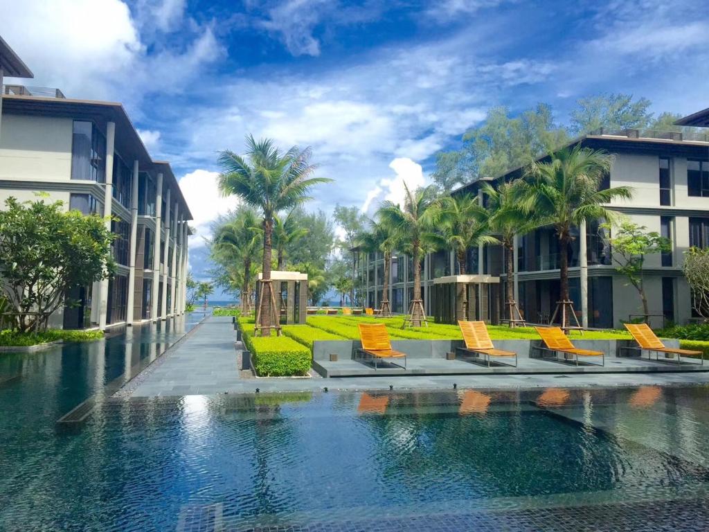 a pool at a resort with chairs and palm trees at Baan Mai Khao in Mai Khao Beach