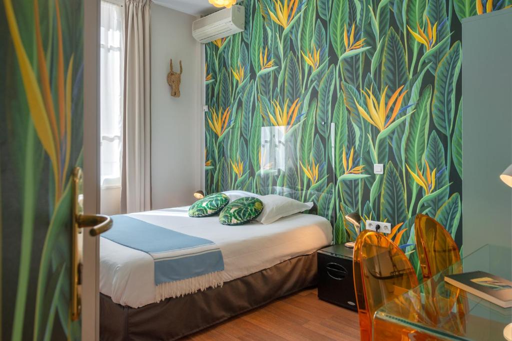 a bedroom with a bed with a green and yellow wallpaper at Hôtel Cecil - Boutique hôtel in Juan-les-Pins