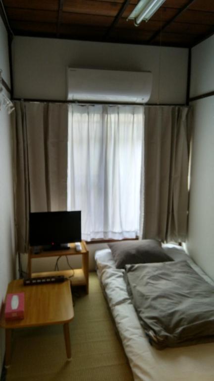 a bedroom with a bed and a desk and a window at Ryokan Nakadaya in Tokyo