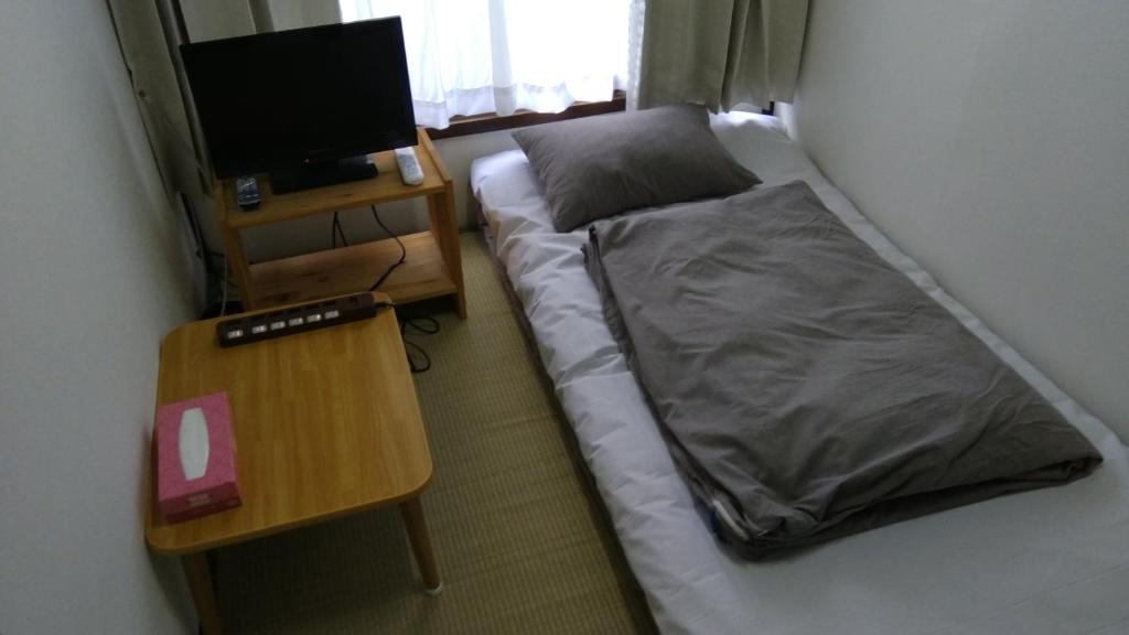 a small bedroom with a bed and a table at Ryokan Nakadaya in Tokyo